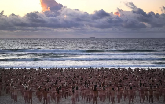naked volunteers pose for tunick artwork on bondi beach